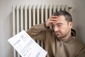 man with hand on his head looking at the gas bill